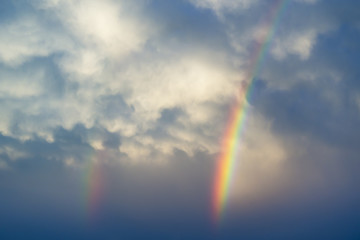 Dramatic double rainbows against stormy blue spring clouds