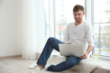 Handsome young man with laptop at home