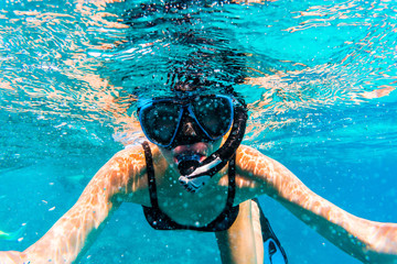 Woman with mask snorkeling in clear sea water