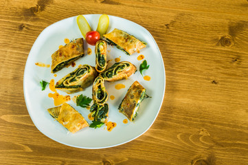 Top view of delicious wrapped crepe with spinach served on a white plate