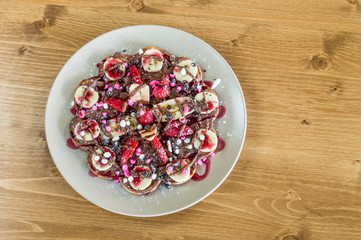 Top view of fruity Belgian waffles with  chocolate and strawberry sauce