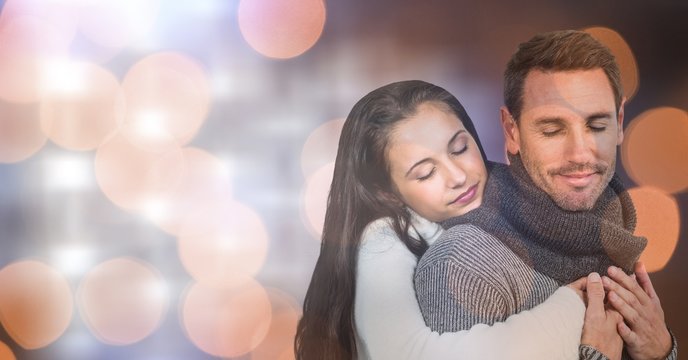 Couple in warm clothes embracing over bokeh