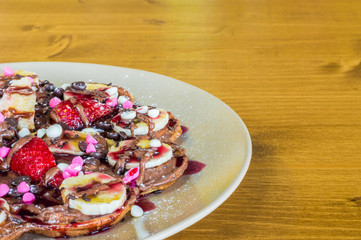 Closeup of fruity Belgian waffles with  chocolate and strawberry sauce