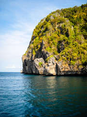 Great and large rocks in the ocean. Small islands with green forest and palms. Blue sky with...