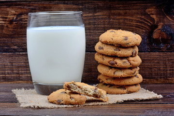 Glass with milk and cookies on wooden background