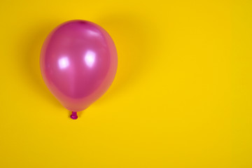 Inflated pink air balloon on the yellow surface