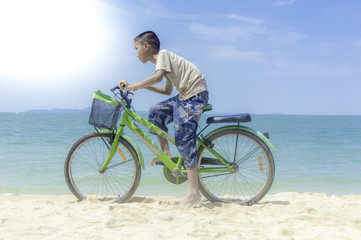 Happy little boy ride bicycle playing on the beach.