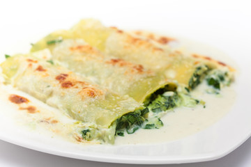 Spinach and cheese cannelloni preparation : Served spinach and cheese cannelloni on a white dish