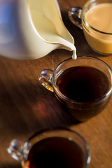 Creamer Pouring Cream into Three Glass Coffee Mugs 3