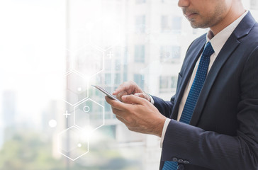 Business man using smart phone on window with futuristic technology connection shape over the network connection background