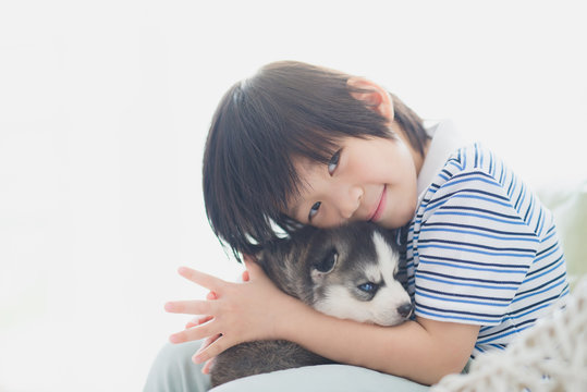 Cute asian child playing with siberian husky puppy