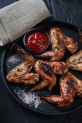 Close-up of bbq chicken wings in a frying pan, selective focus, studio shot