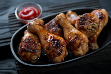Close-up of grilled chicken legs served in a frying pan, selective focus, shallow depth of field