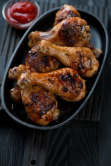 Close-up of a frying pan with grilled chicken legs, selective focus, studio shot