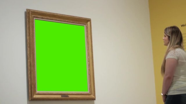 Woman in museum art gallery looks at generic green screen painting