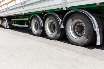 Fototapeta na wymiar wheels of heavy truck with trailer on gray asphalt road