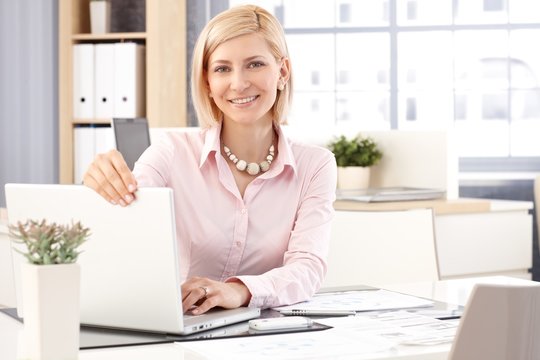 Happy female receptionist with laptop computer