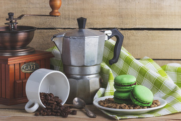 Green macarons on the plate, cup, coffee pot and plaid napkin