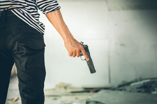 Robber holding a gun at abandoned building. Low key photo and selective focus. criminality concept.