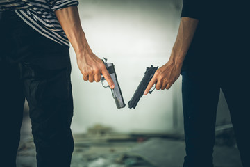 Two Robbers holding a gun at abandoned building. Low key photo and selective focus. criminality concept. - obrazy, fototapety, plakaty