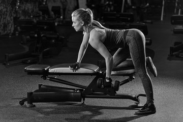 Fototapeta na wymiar Beautiful sporty woman doing power fitness exercise at sport gym. Girl with dumbbell. Black and white.