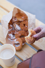 Fast food. Sugar donuts in the hands of the girl. Food on the street - donuts and coffee