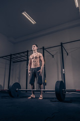 Fototapeta na wymiar bodybuilder standing posing, weights bar barbell, dark gym indoors