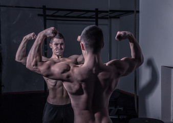 Fototapeta na wymiar bodybuilder, looking at himself in mirror, strong muscular
