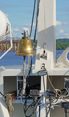 The ship's bell on the bow with elements of the rigging of the ship on a Sunny day vertically