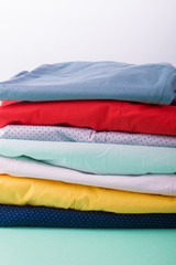 Folded colorful pants and jeans. Stack of bright female trousers. Close up.