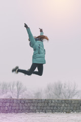 Young girl is jumping in winter snow park. Toned and processing photo