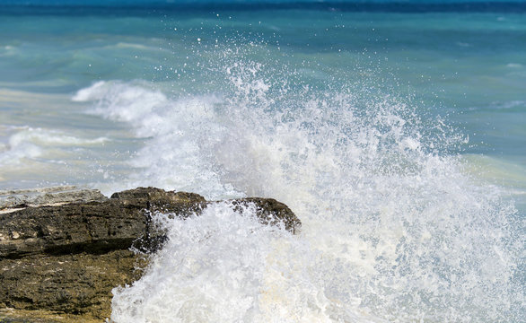 Splashing shore. Coastline of the Caribbean sea. Wave hitting the rocks.