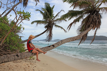 Femme assise sur tronc de cocotier et détente sur plage sauvage de la digue au crépuscule