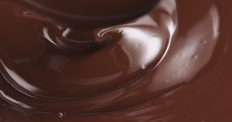 premium dark melted chocolate being poured from spoon in left part of frame from above toned, 4k photo