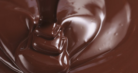 premium dark melted chocolate being poured from spoon in left part of frame from above toned, 4k photo