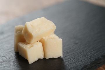 Fototapeta na wymiar pieces of hard parmesan cheese on slate board, closeup photo