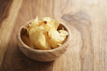 potato chips with herbs in wood bowl on rustic table