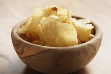 potato chips with herbs in wood bowl on rustic table