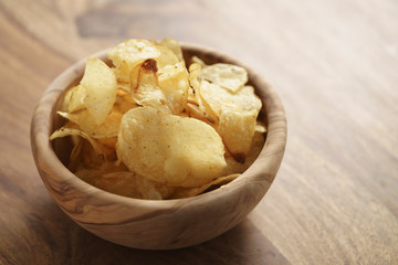 potato chips with herbs in wood bowl on rustic table