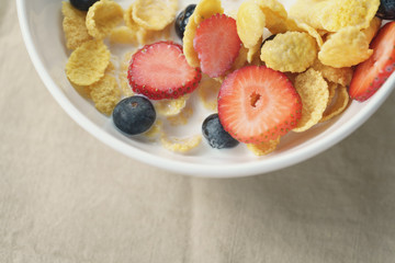 healthy breakfast with corn flakes and berries in white bowl, slightly toned photo