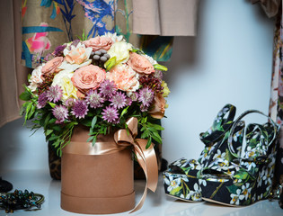 A beautiful bouquet of beige roses in a box for hats is next to women's shoes and handbag