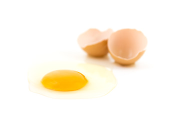raw fresh egg on white surface, cracked eggshell on background, blurred
