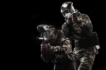 Heavily armed masked paintball soldier isolated on black background. Ad concept.