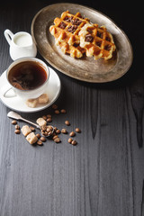 Homemade belgian waffles, white ceramic cup of coffee, milk, tea