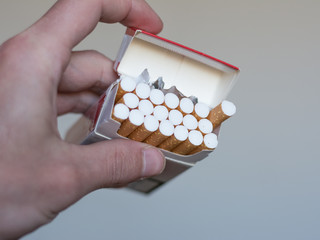 Takes a cigarette from a red white bundle