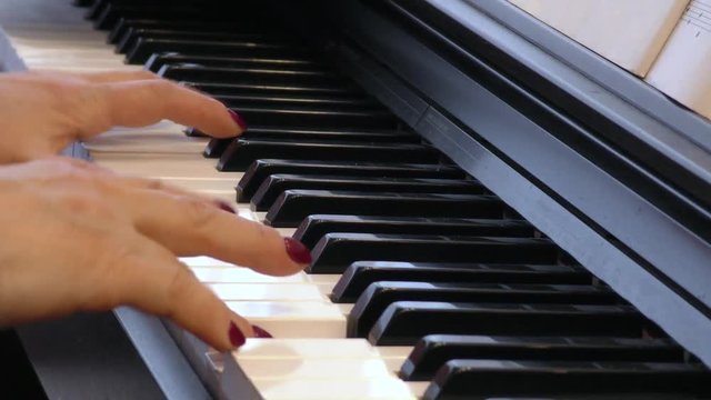 Pianist plays the piano. Hands of a woman playing music on a keyboard instrument. Fingers on the keys.