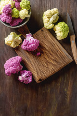 Rainbow of organic cauliflower and Romanesco broccoli on wooden table.