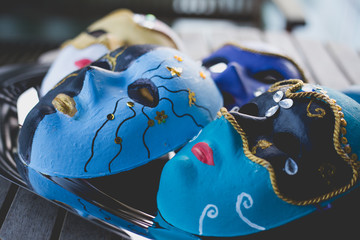 Closeup of beautiful masks made in the venetian style with acrylic paint and decoration, on the silver tray and wooden table