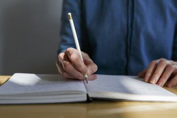 hand of a woman writing in a notebook with a pencil
