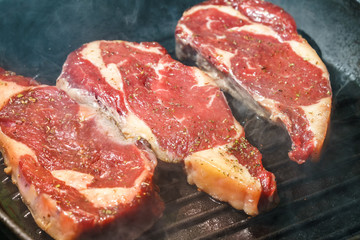 Raw Ribeye Steak with Herbs and Spices, frying on grill pan